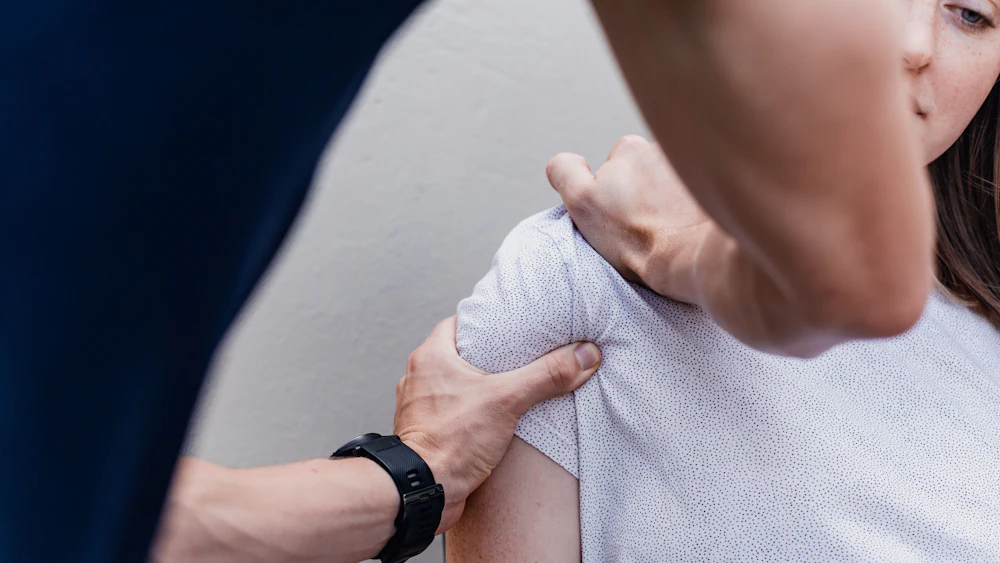 Therapeut untersucht die Schulter einer Patientin