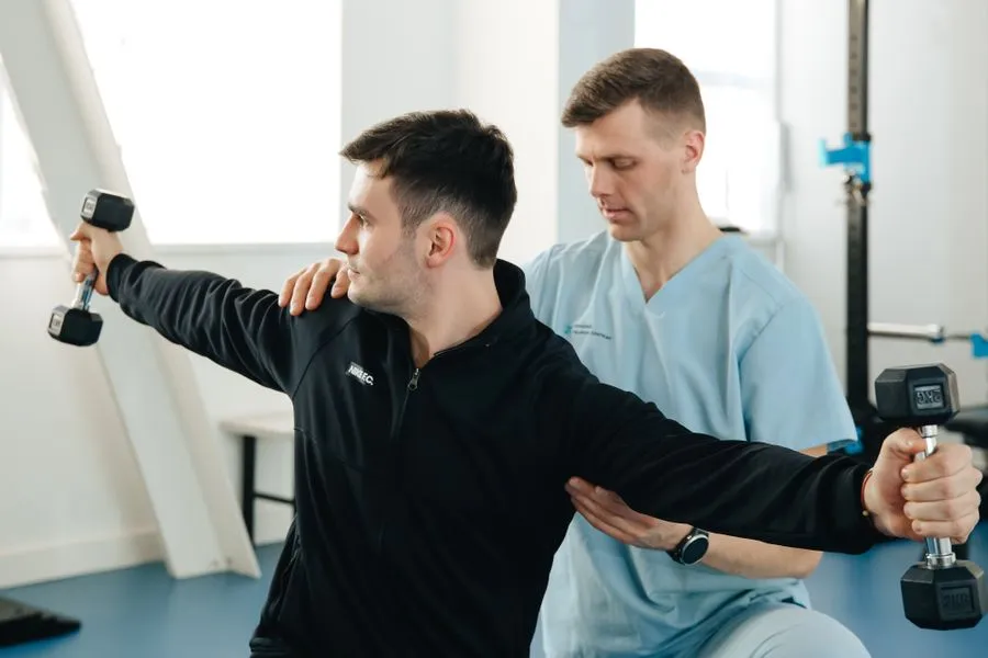 Physiotherapeut betreut einen Patienten beim Krafttraining
